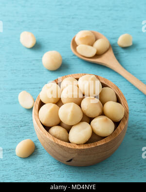 Macadamia Nüsse in der Schale auf der blauen Holztisch Stockfoto