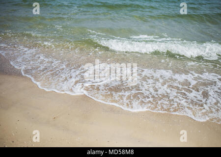 Schönen tropischen Strand in der Morgensonne. Charmante schäumenden Wellen im Meer und gelbem Sand Textur. Stockfoto