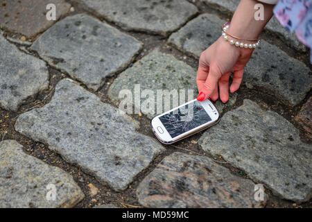 Person Kommissionierung gebrochen Smart Phone (Risse) der Boden Stockfoto