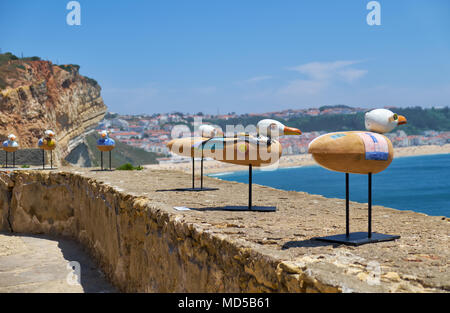 NAZARE, PORTUGAL - 26. JUNI 2016: Eine Installation kunst auf dem Nazare Leuchtturm (Farol da nazare) - die Möwen auf der Brüstung mit Nazare abschleppen Stockfoto