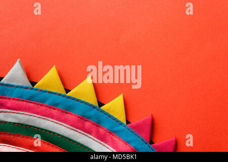 Close-up runde bunte Handgemachte gestreiften Stoff mit dreieckiger Rand auf rotem Hintergrund genäht. Stockfoto