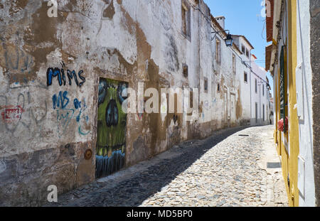 EVORA, PORTUGAL - Juli 1, 2016: erschreckende Graffiti der Schädel auf die blockierte Tür in der Wand der gepflasterte Straße von Evora. Alente Stockfoto