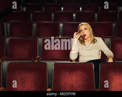 Eine Frau sitzt in einem alten theater saugen an einem Lutscher. Stockfoto