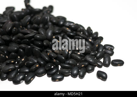 Stapel von frischen, rohen ungekochten schwarze Bohnen auf weißem Hintergrund. Schließen oben mit geringer Tiefenschärfe. Stockfoto