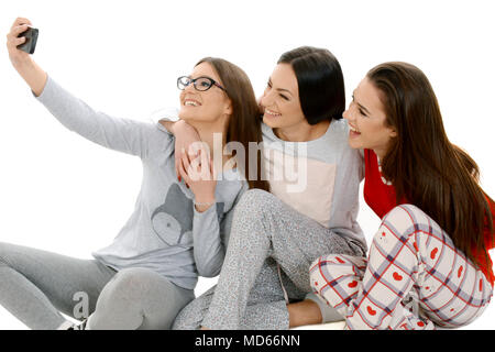 Drei schöne glückliche Mädchen in ihren Pyjamas unter selfie mit Smartphone. Freundschaft, Menschen und pyjamaparty Konzept - glückliche Freunde Stockfoto