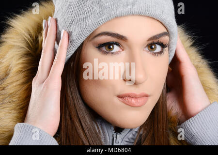 Junge attraktive Frau mit Schirmmütze und Pelzjacke Stockfoto