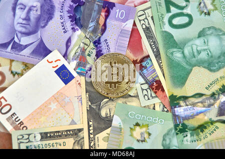 MONTREAL, KANADA - 10. MÄRZ 2018: Bitcoin cryptocurrency gold coin und Logo auf Euro, US-Dollar, kanadische Dollar Banknoten. Stockfoto