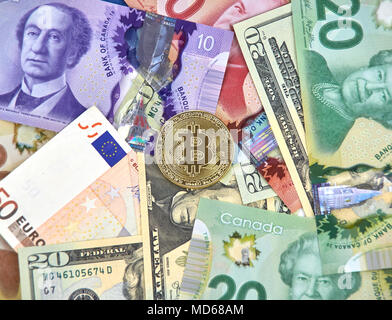 MONTREAL, KANADA - 10. MÄRZ 2018: Bitcoin cryptocurrency gold coin und Logo auf Euro, US-Dollar, kanadische Dollar Banknoten. Stockfoto