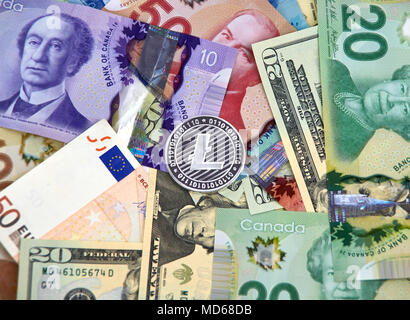 MONTREAL, KANADA - 10. MÄRZ 2018: Litecoin cryptocurrency Silber münze und Logo auf Euro, US-Dollar, kanadische Dollar Banknoten. Stockfoto