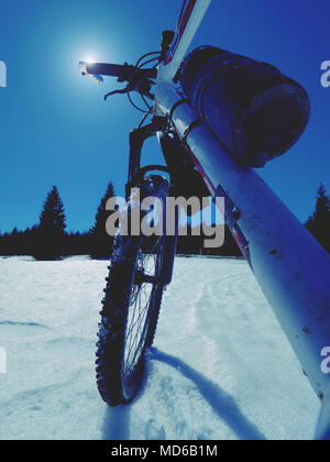 Mountainbike Urlaub im Pulverschnee. Verlorene weg in tiefe Schneeverwehungen. Schneeflocken schmelzen in dunklen off road Reifen. Winter in das Feld ein. Stockfoto