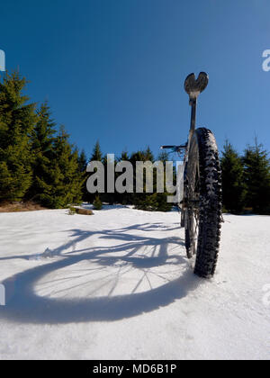 Mountainbike Urlaub im Pulverschnee. Verlorene weg in tiefe Schneeverwehungen. Schneeflocken schmelzen in dunklen off road Reifen. Winter in das Feld ein. Stockfoto