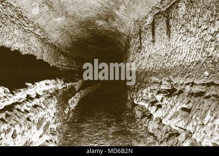 Die alte Sandstein Tunnel, Höhlen abgebaut. Die Höhle. Sandstein Tunnel feuchten Wänden. Trockene Kanal in den felsigen Untergrund geschnitzt. Solarisation Wirkung Stockfoto