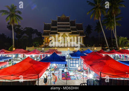 Night Market und beleuchtete Haw Pha Bang Tempel, auch als Royal oder Schlosskapelle, neben dem königlichen Palast in Luang Prabang, Laos bekannt, in der Dämmerung. Stockfoto