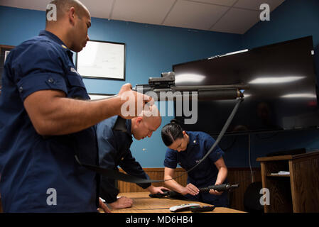 Petty Officer 2nd class Kenny Rosa Rohena Uhren als Petty Officer 2nd class Gabriel Ortiz-Modestti lehrt Petty Officer 3. Klasse Gelb Glover der richtige Weg, eine Schrotflinte an der Coast Guard Station Port Canaveral, Jan. 14, 2018 zu laden, in Port Canaveral, Florida. Rosa, Rohens Ortiz-Modestti und Glover, der bootsmann Mate an der Station Port Canaveral, durchmachen Feuerwaffen Training, um ihre Qualifikationen zu erhalten. (U.S. Coast Guard Foto von Petty Officer 3. Klasse Ryan Dickinson) Stockfoto