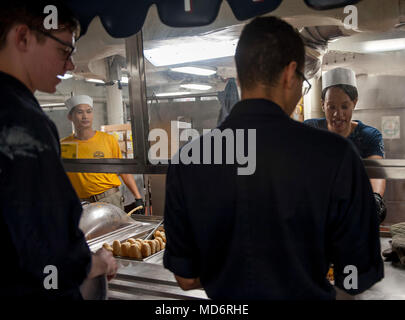 180329-N-JU 894-0003 ATLANTIK (29. März 2018) Chef der Luftfahrt Bootsmann Mate (Handling) Emil Garcia, Links, ein Eingeborener von San Diego, und Chief Aviation Elektriker Mate's Kyla Richardson, von Mount Vernon, New York, Essen servieren, um Soldaten Matrosen auf dem Achterdeck Chaos Decks an Bord der Flugzeugträger USS George H.W. Bush (CVN 77). Das Schiff ist im Gange, die Erhaltung übungen Träger bereit zu halten. (U.S. Marine Foto von Mass Communication Specialist 3. Klasse Brooke Macchietto) Stockfoto