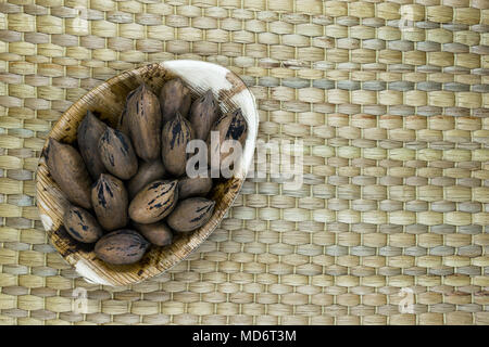 Pekannuss mit der nussschale im Eco natürliche Banana leaf Platte auf natürliche Bambus matte Oberfläche mit freier Speicherplatz Stockfoto