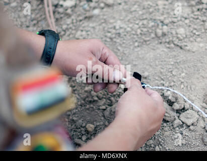 Eine irakische Terrorismusbekämpfung Service die Beseitigung von Explosivstoffen student Rigs einer strahlkabine Kappe zu Sprengstoff aus einem ISIS-Cache während einer Übung im Bagdad diplomatische Unterstützung komplexer beschlagnahmt detonieren, 28. März 2018. Koalition Mitglieder waren vor Ort zu helfen, beraten und CTS mit der richtigen Beseitigung von explosionsfähigen Kriegshinterlassenschaften, um ihre Fähigkeiten zu verbessern und die Stabilität und Normalität in den Irak bringen. (U.S. Armee Foto von Sgt. William A. Parsons) Stockfoto