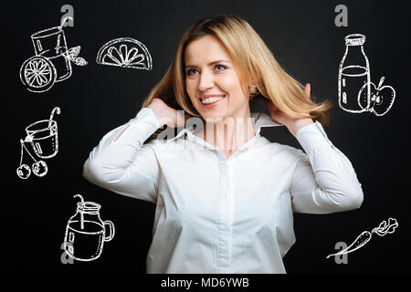 Fröhliche junge Frau lächelnd und Ihr Haar berühren Stockfoto