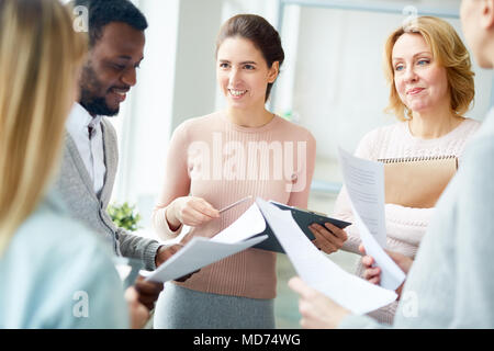 Multi-ethnischen Gruppe von Managern im Kreis im geräumigen Großraumbüro und den Austausch von Ideen über die Start-up-Projekt stehen Stockfoto