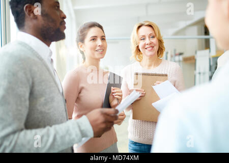 Engagiertes Team von Managern holding Ablagen und Dokumente in Händen, während in produktive Projekt Diskussion auf geräumige offene Büro Stockfoto