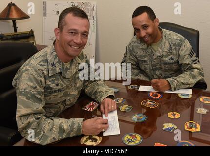 Oberst Houston Cantwell, 49th Wing Commander, und Chief Master Sgt. Barrington Bartlett, 49th Wing command Chief, unterzeichnen Sie oben eine Spende an die Air Force Hilfsfonds Holloman Air Force Base, N.M., 26. März 2018 zu machen. Die vier Organisationen, die in AFAF beteiligt sind, sind die Air Force Aid Society, Allgemeine und Frau Curtis E. LeMay Foundation, die Luftwaffe Dörfer, und die Air Force Soldaten Dorf. (U.S. Air Force Foto: Staff Sgt. Timothy Young) Stockfoto