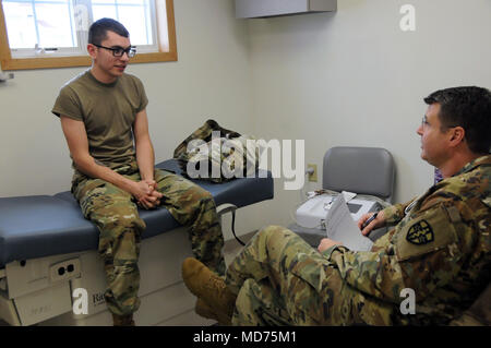 Spc. Jesse White, einem Fachmann in der 7409Th Truppe Medizinische Klinik zugeordnet, demonstriert den Prozess ein Soldat wird durch beim Besuch der TMC gehen. Weiß visits Maj. Jonathan Hutchings, eine Familie Praxis Arzt simulieren, um die Soldaten mit ihren Provider haben wird. ARMEDCOM Soldaten zu 7212Th medizinische Unterstützung und 7409Th Truppe Medizinische Klinik zugeordnet unterstützt medizinische Soldat Bereitschaft Verarbeitung und Truppe Medizinische Klinik Operationen während ihrer Ausbildung am Fort McCoy, Wisconsin am März 1-15, 2018. Die erfolgreiche proof-of-concept-Programm ist Implementierung Stockfoto