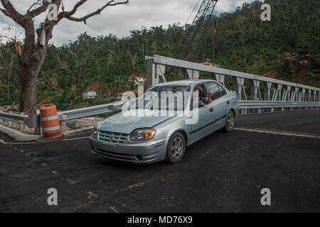 Utuado, Puerto Rico. März 13, 2018 -- Eine glückliche Bewohner von Río Abajo ist einer der ersten sein Auto über die neue Brücke in seiner Gemeinschaft zu fahren. Nach dem Hurrikan María durch die Insel Riss, der starke Regen brach die bisherige Brücke verlassen mehr als 25 Familien isoliert. Heute, dank der Anstrengungen der örtlichen, Landes- und Bundesbehörden, hat die Gemeinschaft eine neue Brücke. Die FEMA/Eduardo Martínez Stockfoto