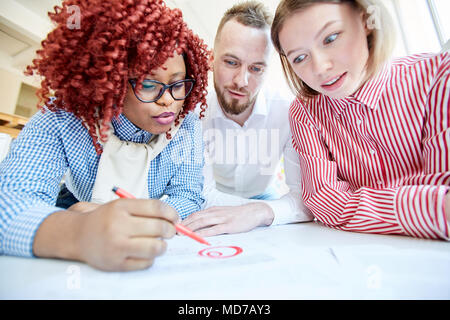Multiethnische Gruppe der männlichen und weiblichen Mitarbeiter im Büro lesen Dokument und die Hervorhebung wichtiger Informationen, Low Angle View Stockfoto