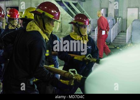 180403-N-ist 471-0159 Yokosuka, Japan (Apr. 3, 2018) Segler Auf der Marine vorwärts bereitgestellt Flugzeugträger USS Ronald Reagan (CVN 76) Praxis Schlauch Handhabung Techniken während der Ausbildung an der Yokosuka Brandbekämpfung und Beschädigung der Anlage zugeordnet. Ronald Reagan, das Flaggschiff der Carrier Strike Group 5, bietet eine Bekämpfung bereit, Kraft, schützt und verteidigt die kollektive maritime Interessen seiner Verbündeten und Partnern in der Indo-Asia-Pazifik-Region. (U.S. Marine Foto von Mass Communication Specialist 1. Klasse Glenn Schlachtung) Stockfoto
