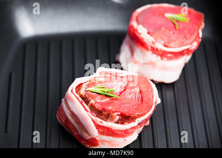 Rohen steak Filet Mignon in einem gegrillten Pan close-up mit einem Zweig Rosmarin. Thema der leckeren und gesunden Speisen. Stockfoto