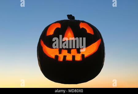 Noch immer leben eines glühenden geschnitzten Kürbis oder Jack o'Lantern leuchtet von innen gegen eine twilight Hintergrund Stockfoto