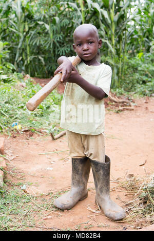 Uganda. 17. Juni 2017. Ein wenig Ugandischen boy Holding einer Hacke. Stockfoto