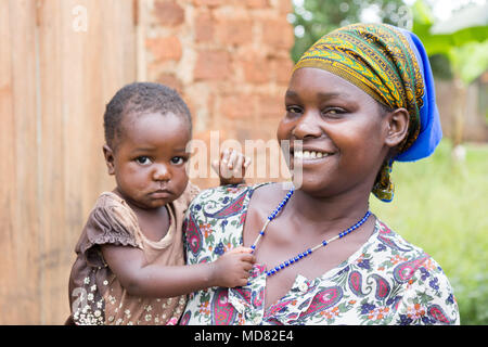 Uganda. Juni 09 2017. Eine glückliche und lachende Junge afrikanische Frau, die ihr Kind in die Arme. Stockfoto