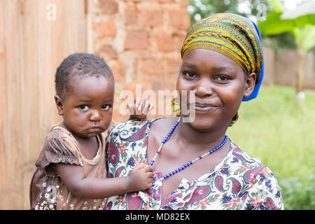 Uganda. Juni 09 2017. Eine glückliche und lachende Junge afrikanische Frau, die ihr Kind in die Arme. Stockfoto