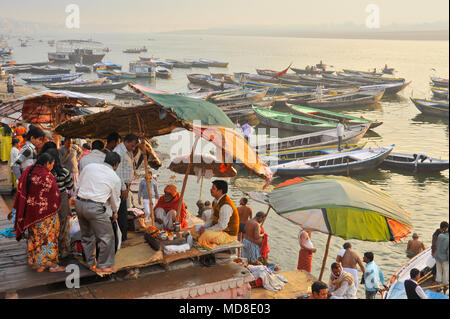 Hinduistische Pilger empfangen Segen von einem Priester unter einem Sonnenschirm von der Ganges in Varanasi ghats Stockfoto