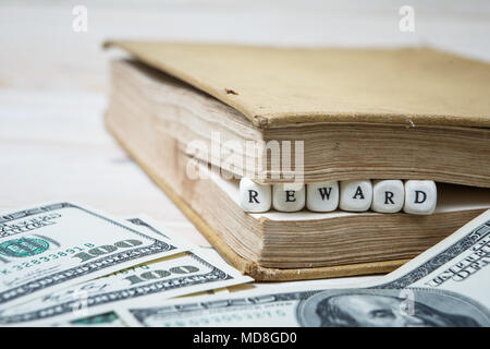 Wort Belohnung in Holz- Bausteine im Buch auf weiße Holztisch geschrieben Stockfoto