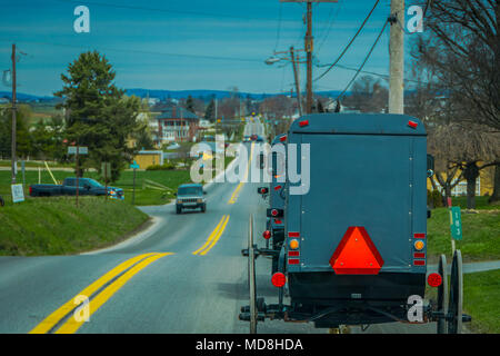 Pennsylvania, USA, April, 18, 2018: Blick auf die Rückseite eines altmodischen, Amish Buggy mit einem Reiten auf Schotter Landstraße Stockfoto