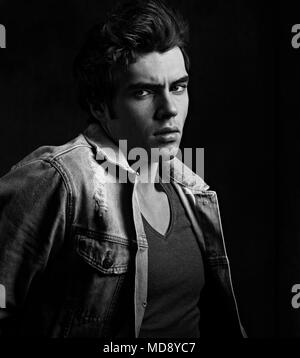 Denken Ernst charismatischen Mann in Jeans suchen auf dunklen Schatten dramatisch hellen Hintergrund. Closeup Portrait. Art. Schwarz und Weiß Stockfoto