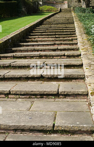 Yorkstone Schritte durch eine Mauer aus Stein in einem Garten in Kent Stockfoto