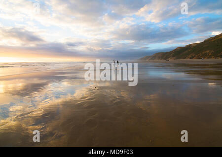 Zwei Menschen laufen in einem Strand bei Sonnenuntergang in der Region Northland auf der Nordinsel Neuseelands Stockfoto