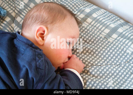 Blick von oben auf die baby boy Daumenlutschen im Bett, Griechenland Stockfoto