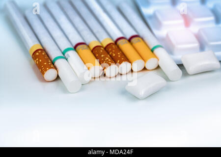 Nikotin Kaugummi im Blister in der Nähe von Pile der Zigarette. Quit Smoking durch Nikotinkonsum Gummi für Entlastung von Nikotin Entzugserscheinungen. Medizin für Stockfoto