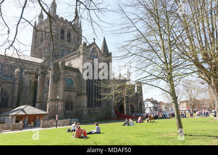 Die Menschen nehmen eine Pause von der Arbeit auf dem Rasen außerhalb Hereford Cathedral. Stockfoto