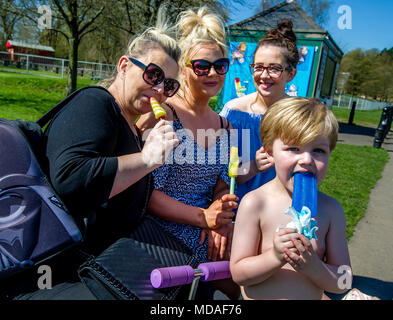 Bolton, Großbritannien. April 19, 2018. Strahlendem Sonnenschein sahen die Zuschauer in Scharen zu Moos Bank Park in Bolton am Nachmittag auf, was bisher erwartet, ist der heißeste Tag des Jahres zu sein. Die Temperaturen sind auf die Mitte 20 Celsius und die Hitzewelle wird bis zum Wochenende zu erreichen. Eine Familie mit kühlen Eis am Stiel nach unten. Bild von Paul Heyes, Donnerstag, 19 April, 2018. Credit: Paul Heyes/Alamy leben Nachrichten Stockfoto