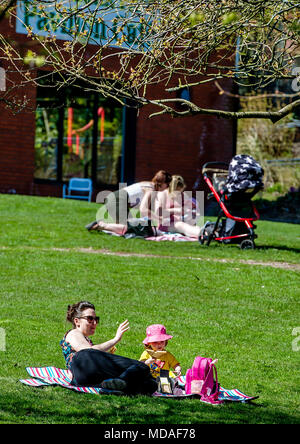 Bolton, Großbritannien. April 19, 2018. Strahlendem Sonnenschein sahen die Zuschauer in Scharen zu Moos Bank Park in Bolton am Nachmittag auf, was bisher erwartet, ist der heißeste Tag des Jahres zu sein. Die Temperaturen sind auf die Mitte 20 Celsius und die Hitzewelle wird bis zum Wochenende zu erreichen. Picknick im Park Zeit für diese jungen Familien. Bild von Paul Heyes, Donnerstag, 19 April, 2018. Credit: Paul Heyes/Alamy leben Nachrichten Stockfoto