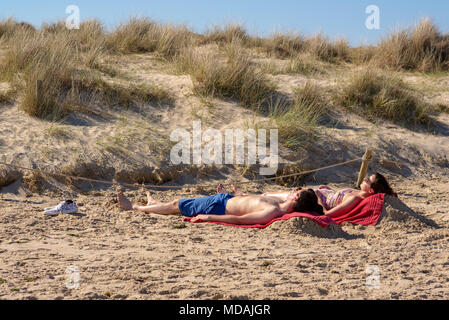 Paar auf dem Sandstrand von Studland, Dorset, UK, 19. April 2018, in der Sonne und genießen die Hitzewelle auf, was die heißesten April Tag für fast 70 Jahre sein könnte. Stockfoto
