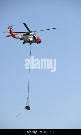 Ein Coast Guard HH-60 Hubschrauber Crew von Coast Guard Air Station San Deigo transportiert Teile eines neuen Navigationshilfen zum Anaheim Bay East Jetty Licht 6 Naval Waffen Station Seal Beach, Calif., 18. April 2018. Die HH-60 Hubschrauberbesatzung transportiert 3 verschiedene Teile, wo Mitglieder der Küstenwache Aids zur Navigation Team Los Angeles-Long Beach, die neue Navigationshilfe montiert. U.S. Coast Guard Foto von Petty Officer 3. Klasse DaVonte' Knochenmark freigegeben. Stockfoto