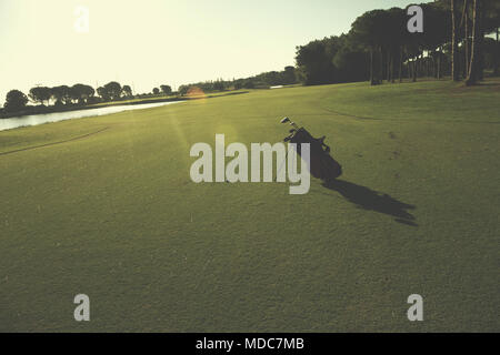 Golfbag mit Club und Ball vorne am wunderschönen Sonnenaufgang auf Kurs Stockfoto