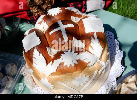 Traditionelle hausgemachte dekoriert Serbischen Ostern Brot am grünen Tisch und Stücke Brot als Vertreter Jesu Leib, im Freien an einem sonnigen Tag Stockfoto