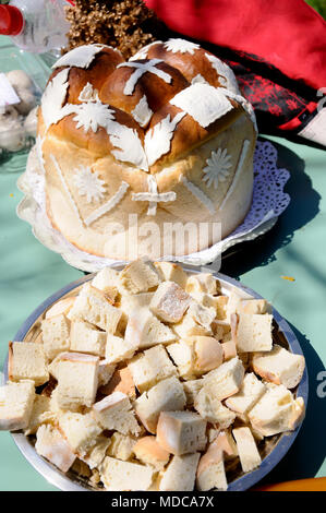 Traditionelle hausgemachte dekoriert Serbischen Ostern Brot am grünen Tisch und Stücke Brot als Vertreter Jesu Leib, im Freien an einem sonnigen Tag Stockfoto